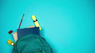 Colorful school supplies moving from school bag on blue background. Stop motion