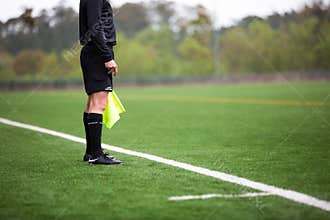 Soccer or football referee standing on green artificial grass field