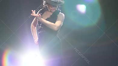Dancer is dancing a Spanish incendiary dance. Black background. Llight from behind