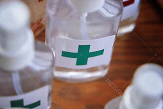 Alcohol antiseptics with the green cross logo on wooden table.