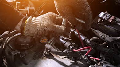 Mechanic in gloves unscrews detail of broken automobile