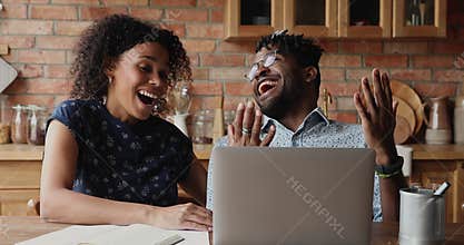 Overjoyed African couple look on laptop screen give high five