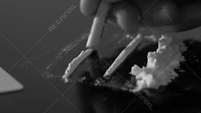 A rolled banknote snorting a line of cocaine powder. Drug abuse. Sniffing cocaine lines. White powder on black table.