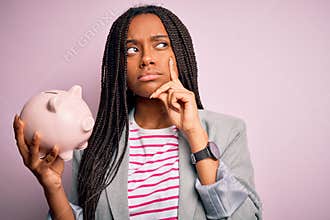 Young african american business woman saving money on piggy bank over  background serious face thinking about question,