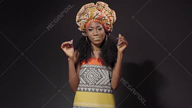 Dancing wearing traditional dressed beautiful Afro American young woman dancing and smile looking at camera sideways