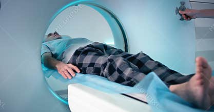 Senior male patient entering modern CT machine near doctor