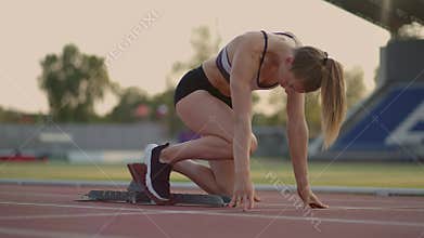 Female athlete starting her sprint on a running track. Runner taking off from the starting blocks on running track