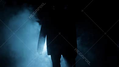 Cinematic slow motion shot of a gangster mafia man walking with a gun in his hand. Dramatic shot of a man in dark lighting with so
