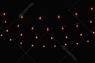 String lights glass bulbs garland with glowing spirals on black background