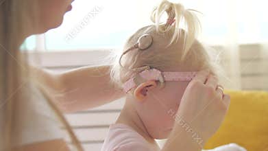 Concept of hearing impairment and their treatment. Mom connects a cochlear implant for her daughter