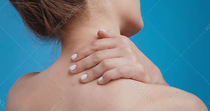 Close up shot of young woman massaging her neck, applying treatment cream to sore muscles, back view
