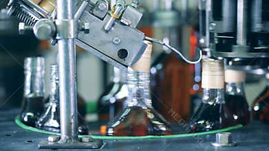 Spinning conveyor is closing bottles with cognac