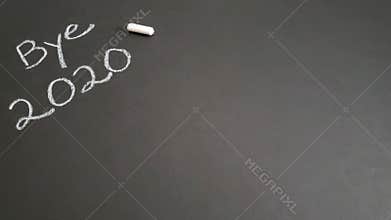 Bye 2020 message with a piece of white chalk on a black background