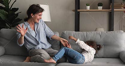 Energetic overjoyed small kid girl playing with mum or nanny.