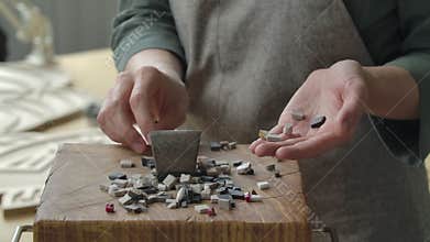 Male hands collect broken pieces of stone to lay out a mosaic pattern. Preparation of stone material for laying out a