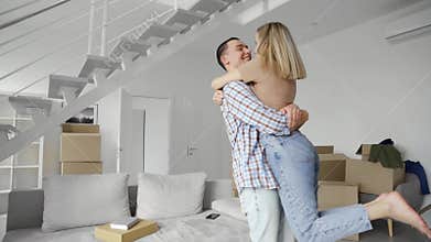 Happy young family couple embracing kissing at new home at moving day.