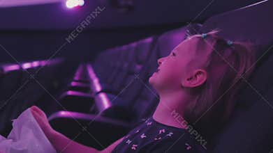 A little girl sitting in the planetarium auditorium looks up and laughs.