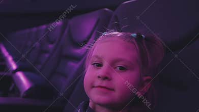 A little girl sitting in the planetarium auditorium looks up and laughs.