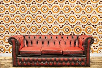 Retro styled image of an old sofa against a vintage wallpaper wa