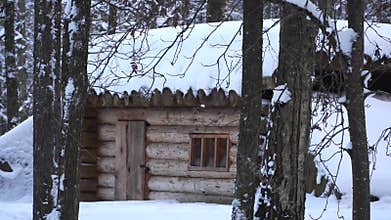 The dugout building: a snow-covered log house in a forest