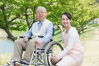 Senior man sitting on a wheelchair with caregiver