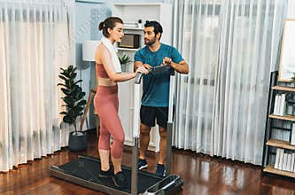 Athletic and sporty couple running on elliptical running machine at gaiety home.