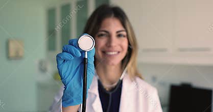 Young woman cardiologist physician holds stethoscope looking at camera