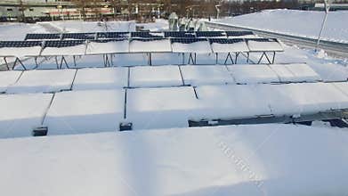 Snow-covered solar batteries near city street with