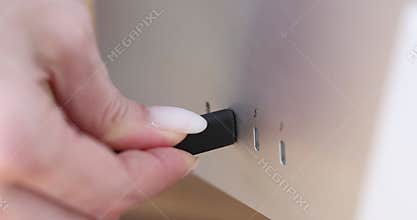 Person hand connects black USB-C or Type C power cable to computer or monitor
