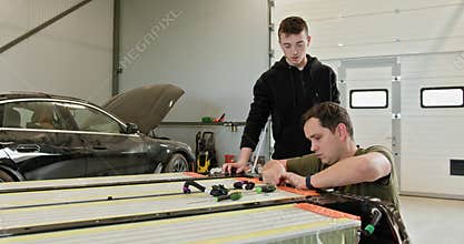 Technicians Repairing Lithium-Ion Battery In Car Workshop