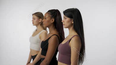 Portrait of young multiethnic models on white background close up. Group of three appealing multiracial girls standing