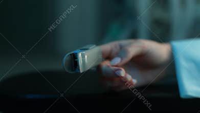 Close-up cropped shot of unrecognizable female hand with pulse oximeter on finger on operating table under anesthesia