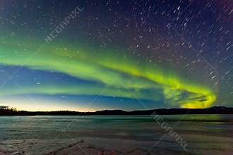 Northern Lights and morning dawn over frozen lake