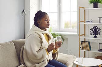 Sick young africanamerican woman feels unwell and is going to drink medicine.