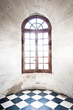 Grungy arched window inside old building.