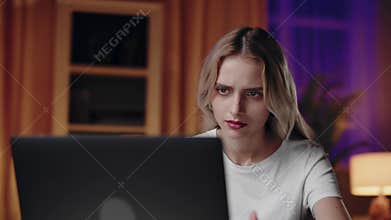 Young woman is comfortably working on her laptop in the evening at her home office