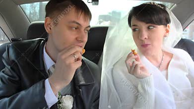 happy bridegroom and bride sits in car and eats
