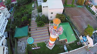 People walk by street near beacon at summer day.