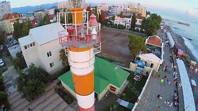 People walk by quay near beacon in coastal town at