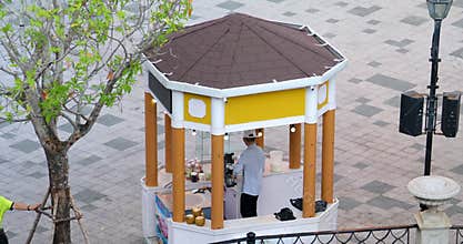 Phu Quoc Island Vietnam 06.16.2024 ice cream seller preparing for working day in small orange gazebo man cleaning