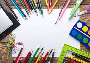 School stationery frame on wooden background: paper, pencil, brush, scissors, folders, abacus,