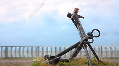 Girl Spreads Arms Like a Bird on an Old Anchor Monument