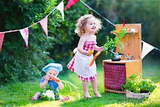 Beautiful little kids playing with toy kitchen in the garden