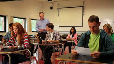 Lecturer handing out papers to his students in classroom