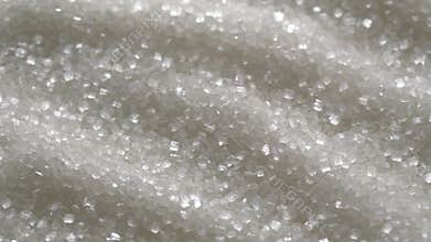 Slow-motion shot of a golden spoon scooping coarse white sugar crystals with sparkling texture