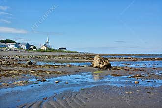 Blue and brown beach with the village in the background, Gaspésie, Quebec, Canada