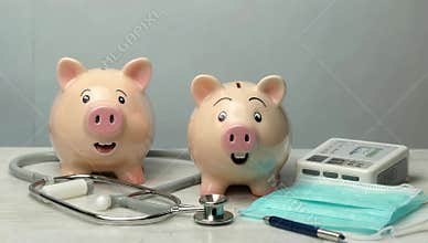 Two piggy banks symbolize healthcare savings with stethoscope and medical equipment nearby