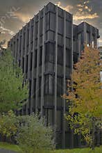 Modern geometric office building with vertical window shades surrounded by autumn trees at sunset