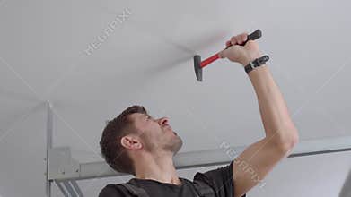 Man hammering nail-in anchor into ceiling