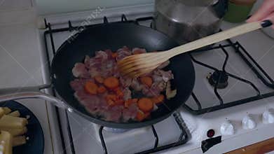Person cooking chicken and carrots in wok